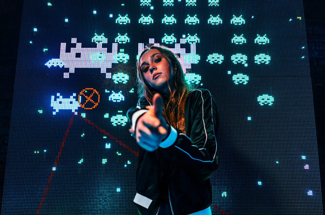 Woman pointing at a camera with space invaders background